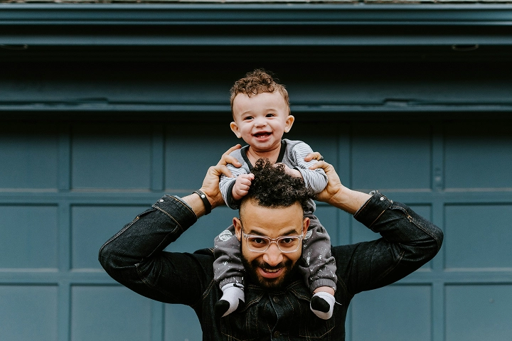 A father holding his toddler son on his shoulders